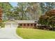 Charming single story brick home with a well-manicured lawn, mature trees, and attached two-car garage at 1152 Old Coach Rd, Stone Mountain, GA 30083