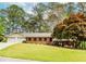 Charming single story brick home with a well-manicured lawn, mature trees, and attached two-car garage at 1152 Old Coach Rd, Stone Mountain, GA 30083