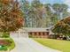 Charming single story brick home with a well-manicured lawn, mature trees, and attached two-car garage at 1152 Old Coach Rd, Stone Mountain, GA 30083