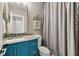 Well-lit bathroom with a blue vanity, granite countertop, framed mirror, and a shower with gray patterned curtain at 1129 Cordia Nw Ave, Atlanta, GA 30318