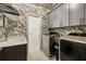 Well-appointed laundry room with floral wallpaper, gray cabinets, sink, and modern washer and dryer units at 1129 Cordia Nw Ave, Atlanta, GA 30318