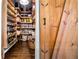 Walk-in pantry with custom wood shelving for ample storage, rustic door, and hardwood floors at 3018 Bradshaw Club Dr, Woodstock, GA 30188