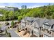 Aerial view of townhomes with brick and stone facade near commercial buildings and mature trees at 705 Abbington River Ln, Atlanta, GA 30339