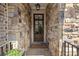 Stone entrance featuring a welcoming doormat, potted flowers, and glass paneled door at 705 Abbington River Ln, Atlanta, GA 30339