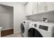 Well-equipped laundry room featuring modern washer/dryer units and overhead storage cabinets at 705 Abbington River Ln, Atlanta, GA 30339