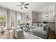 Bright living room with gray sectional sofa, ceiling fan, and windows with view to balcony at 705 Abbington River Ln, Atlanta, GA 30339
