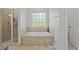 Bright bathroom featuring a walk-in shower, separate soaking tub, and tiled surround at 896 Winn Rd, Douglasville, GA 30134
