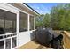 Exterior view of the screened porch with a wooden railing, ceiling fan, and a grill at 896 Winn Rd, Douglasville, GA 30134