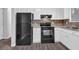 Well-lit kitchen with white cabinets, black appliances, and wood-look floors at 616 Country Lane Dr, Jonesboro, GA 30238