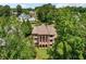 Aerial view of a distinguished brick home nestled among mature trees in a residential area at 6935 Wakehurst Pl, Cumming, GA 30040