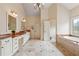 Spacious primary bathroom boasts dual sinks, and soaking tub. Includes light tile flooring and walls with marble countertops at 6935 Wakehurst Pl, Cumming, GA 30040