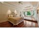Elegant bedroom features a decorative tray ceiling, hardwood floors, and large windows with a view of the backyard at 6935 Wakehurst Pl, Cumming, GA 30040