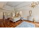 Elegant bedroom featuring hardwood floors, tray ceilings, a ceiling fan and decorative chandelier at 6935 Wakehurst Pl, Cumming, GA 30040
