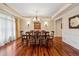Formal dining room featuring hardwood floors, a decorative chandelier, and large windows with curtains at 6935 Wakehurst Pl, Cumming, GA 30040