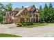 Beautiful home featuring a brick and stone facade, arched windows, and porte-cochere at 6935 Wakehurst Pl, Cumming, GA 30040