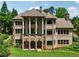 Brick home showcases tall columns, large windows, and private balconies overlooking the property at 6935 Wakehurst Pl, Cumming, GA 30040