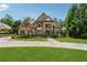Elegant home with stone and brick exterior, circular driveway, and manicured lawn at 6935 Wakehurst Pl, Cumming, GA 30040