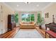 Bright living room featuring hardwood floors, antique bookcase, and large windows with a view at 6935 Wakehurst Pl, Cumming, GA 30040