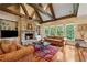Cozy living room with stone fireplace, exposed beams, and large windows offering natural light at 6935 Wakehurst Pl, Cumming, GA 30040