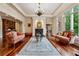 Charming living room with fireplace, hardwood floors, and large windows showcasing the outdoor landscape at 6935 Wakehurst Pl, Cumming, GA 30040