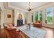 Bright living room featuring hardwood floors, large windows, fireplace, and elegant seating arrangements at 6935 Wakehurst Pl, Cumming, GA 30040