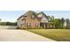 Two-story brick and siding home featuring manicured lawn, a long driveway and attached garage at 209 Brynn Ln, Mcdonough, GA 30252