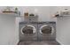 A neat laundry room with side-by-side washer and dryer units, shelving, and neutral decor at 2760 Swansea Ct, College Park, GA 30349