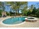 A backyard pool and hot tub combo, with an outdoor stone fireplace and paved patio at 4455 Sirrocco Sw Ln, Lilburn, GA 30047