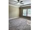 A large bedroom featuring a ceiling fan, neutral walls, carpeted floor and a large window at 5990 Arbor Green Cir, Sugar Hill, GA 30518