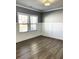 Bright room with hardwood flooring, gray accent walls, white trim, and large windows offering ample natural light at 5990 Arbor Green Cir, Sugar Hill, GA 30518