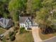 Aerial view of a stunning white brick home with manicured lawn and driveway nestled among mature trees at 125 Ketton Xing, Johns Creek, GA 30097