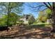 Spacious backyard featuring mature trees, lush landscaping, and a charming view of the home's architecture at 125 Ketton Xing, Johns Creek, GA 30097