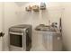 A modern laundry room featuring sleek, front-loading washer and dryer appliances with baskets on a rack shelf at 125 Ketton Xing, Johns Creek, GA 30097