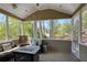 Cozy screened-in porch boasts ample seating, a modern fire pit table, and scenic views of the surrounding greenery at 125 Ketton Xing, Johns Creek, GA 30097