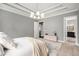 Relaxing main bedroom featuring a modern chandelier, tray ceiling, and a doorway to the ensuite bathroom at 403 Aristides Way, Canton, GA 30115