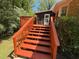 A backyard view of a new red deck, stairs, and landing leading to the yard and an outbuilding at 9214 Brave Ct, Jonesboro, GA 30236