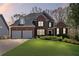 Traditional brick home with a two-car garage, lush lawn, and manicured landscaping at 135 Ardsley Run, Canton, GA 30115