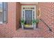 Brick home entrance with black door, potted plants, and stairs at 135 Ardsley Run, Canton, GA 30115