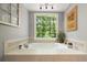 Soaking tub with large window view, stylish tile work, and decorative accents for a relaxing spa-like experience at 1514 Maplewood Ct, Woodstock, GA 30189