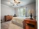 Neutral bedroom with wooden furniture, ceiling fan, and white curtains, exuding a clean and simple aesthetic at 1514 Maplewood Ct, Woodstock, GA 30189