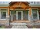 Close-up of a welcoming front porch with stone pillars, rocking chairs, and a wooden porch at 1514 Maplewood Ct, Woodstock, GA 30189