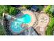 Aerial view of a community pool with chairs, a spa, and a pool house surrounded by trees and landscaping at 1514 Maplewood Ct, Woodstock, GA 30189