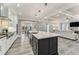Well-lit kitchen with a black island, quartz countertops, and stainless steel appliances, seamlessly flowing into the living room at 2444 Ballantrae Cir, Cumming, GA 30041