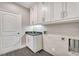 Well-lit laundry room with sink, white cabinets, gray backsplash, and access to the exterior at 2444 Ballantrae Cir, Cumming, GA 30041