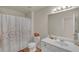 Bright bathroom features a shower with a decorative curtain, a white vanity, and a large mirror at 35 Kestrel Circle, Covington, GA 30014