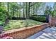 Well maintained backyard with lush lawn, mature trees, and a brick retaining wall at 7512 Portbury Park Ln, Suwanee, GA 30024