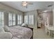 Comfortable bedroom with large windows, a ceiling fan, and a glimpse into an en-suite bathroom and dining area at 7512 Portbury Park Ln, Suwanee, GA 30024