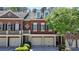 Charming red brick townhome featuring a two-car garage, classic design, and well-maintained landscaping at 7512 Portbury Park Ln, Suwanee, GA 30024