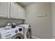 Modern laundry room featuring white cabinets and front-load washing machine and dryer at 7512 Portbury Park Ln, Suwanee, GA 30024