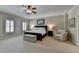 Spacious main bedroom featuring plush carpet, a ceiling fan, and a sitting area for relaxation and comfort at 7512 Portbury Park Ln, Suwanee, GA 30024